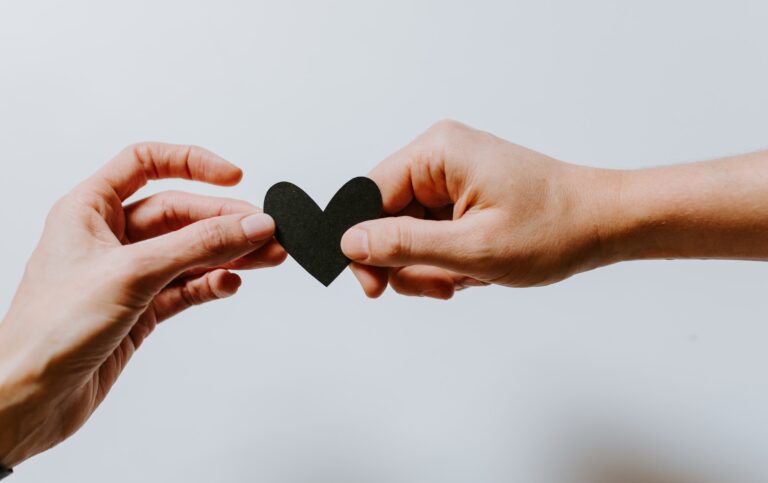 Two hands holding a black heart representing ethical non-monogamy.