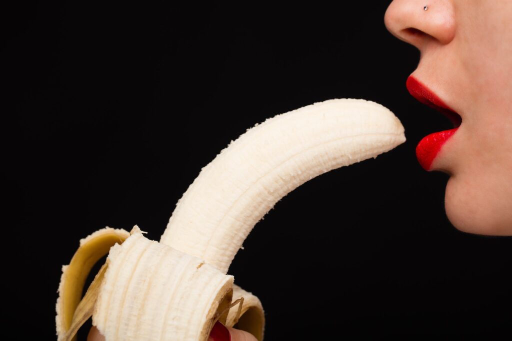 Woman with red lips eating banana.