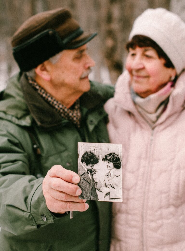 Aging couple hold out a picture of them when they were younger.
