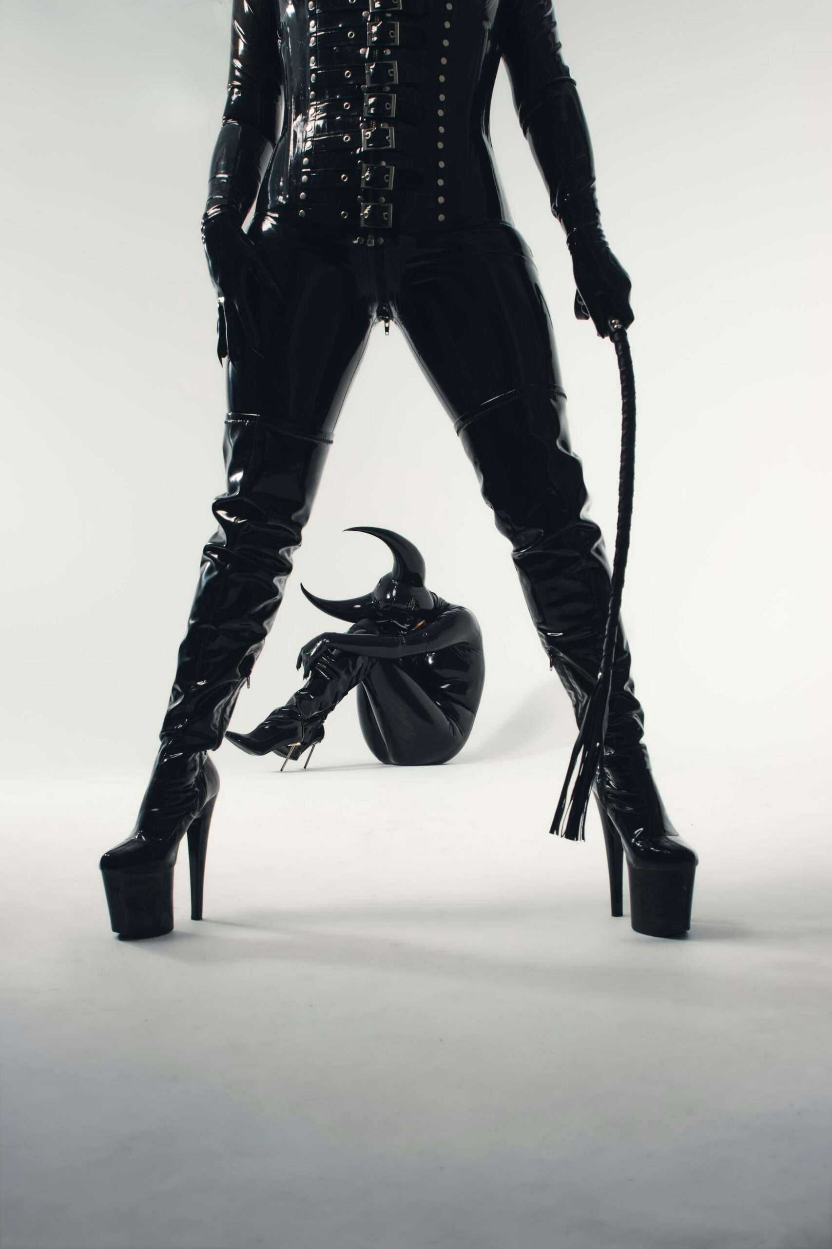 person in latex clothing with riding crop